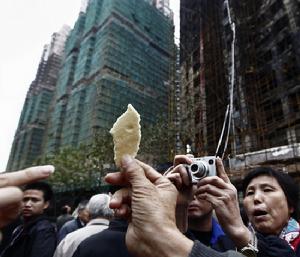 居民舉著起火大樓外墻的保溫材料,認為它并沒有阻燃性。