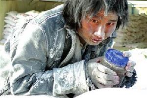 一名工人抱著水杯在成品大白粉堆上發(fā)呆